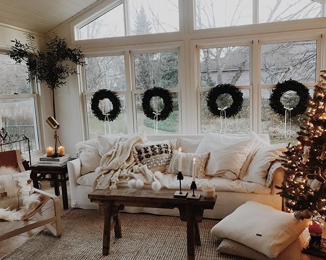 Wieńce świąteczne w oknach salonu z białą sofą