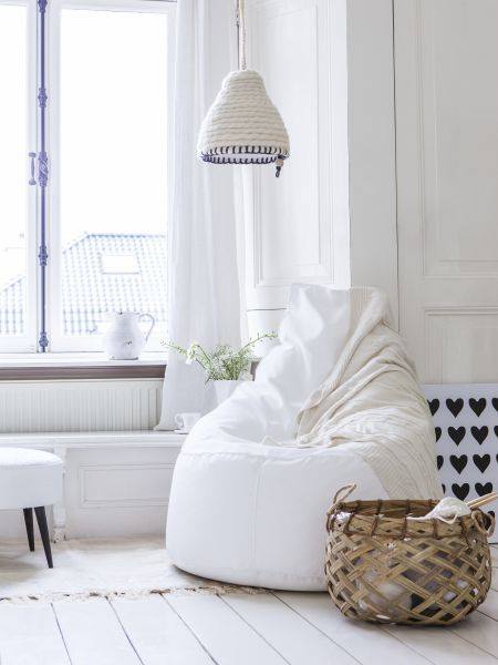 Biały fotel, bambusowy kosz i pleciona lampa