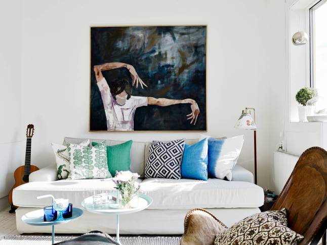 Nowoczesny obraz nad białą sofą w salonie,turkusowe i niebieskie poduszki,biało-czarna poduszka w stylu skandynawskim