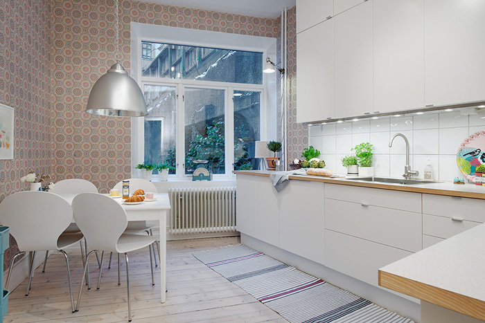 Biała kuchnia z jadalnią w skandynawskim stylu z kolorową tapetą na ścianie