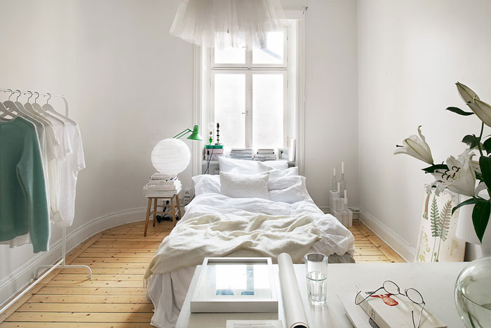 Aranżacja białej sypialni z biurkiem i drewnianą podłogą z naturalnego drewna