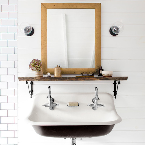 Drewniane lustro i półka na metalowych podporach w białej rustykalnej łazience