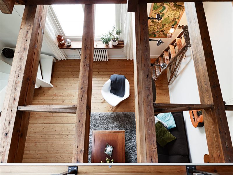 Widok z antresoli na salon z ażurowym sufitem z drewnianych belek