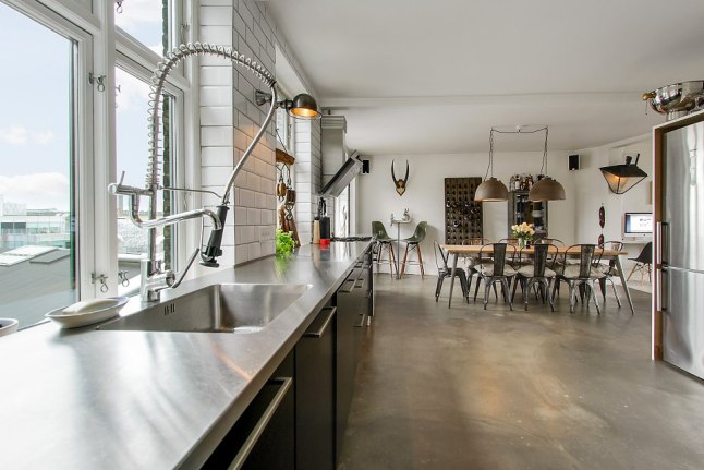 Betonowa podłoga ,industrialne lampy pendant,metalowy stół z drewnianym blatem,metalowe krzesła tolix w otwartej kuchni z jadalnią