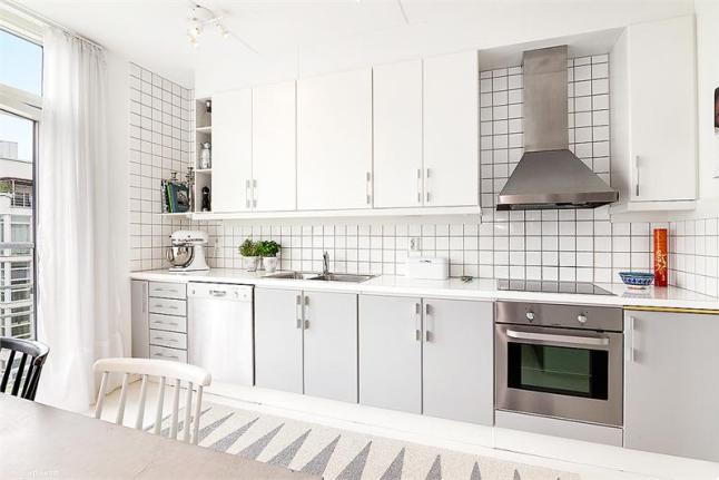Biała kwadratowa płytka na ścianie w skandynawskiej biało-szarej kuchni