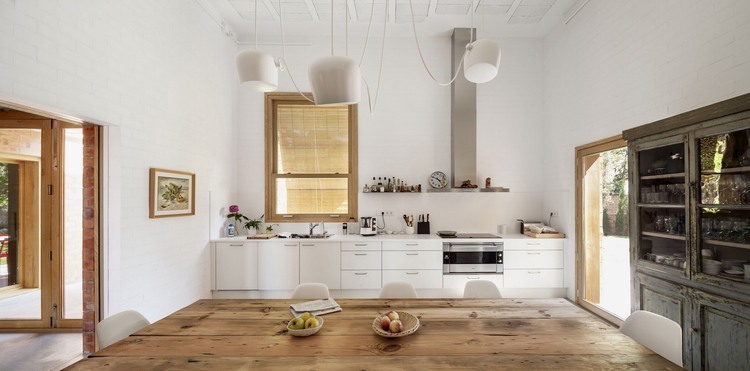 Skandynawska biała kuchnia z drewnianym stołem i szarym francuskim kredensem