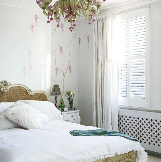 Francuskie łóżko i oliwkowo-różowy porcelanowy  żyrandol w białej sypialni