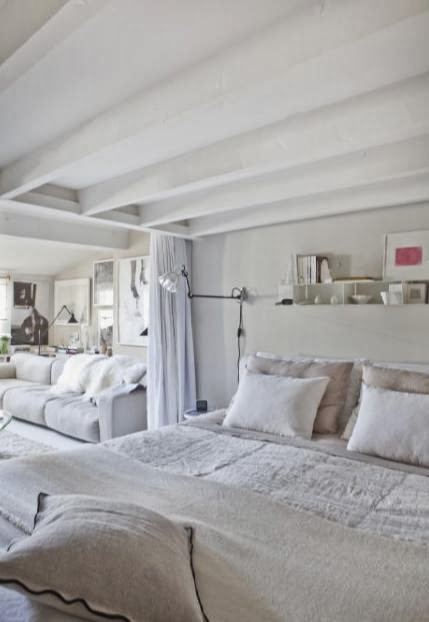 Biało-beżowa sypialnia pod antresolą z zasłonami oddzielającymi je od otwartego salonu