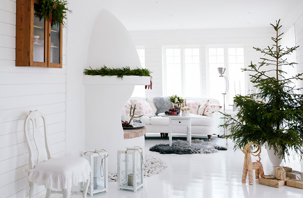 Biały salon z kominkiem w zielonej świątecznej dekoracji