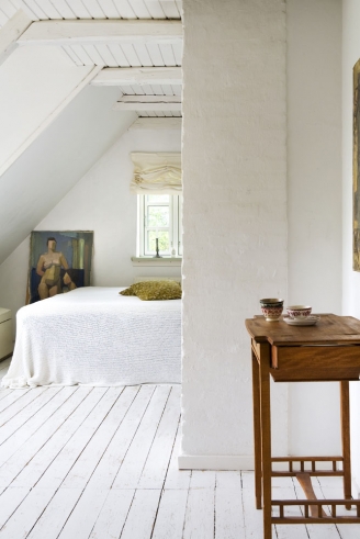 Rolety rzymskie,biala podloga z desek,obrazy i drewniane meble w wiejskiej sypialni