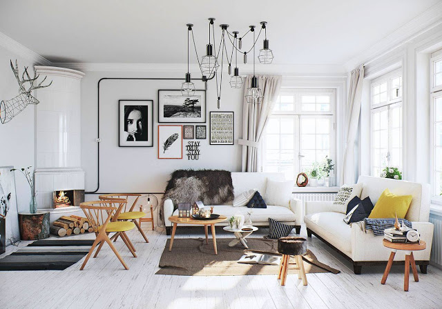 Aranżacja salonu w stylu skandynawskim z ceramicznym białym piecem,drucianymi czarnymi lampami i drewnianymi stolikami kawowymi