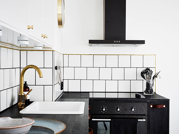 Biało-czarna kuchnia skandynawska z miedziano-chromowaną baterią w stylu industrialnym