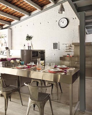 Stalowe meble i krzesła w industrialnej kuchni z białą cegłą na ścianie