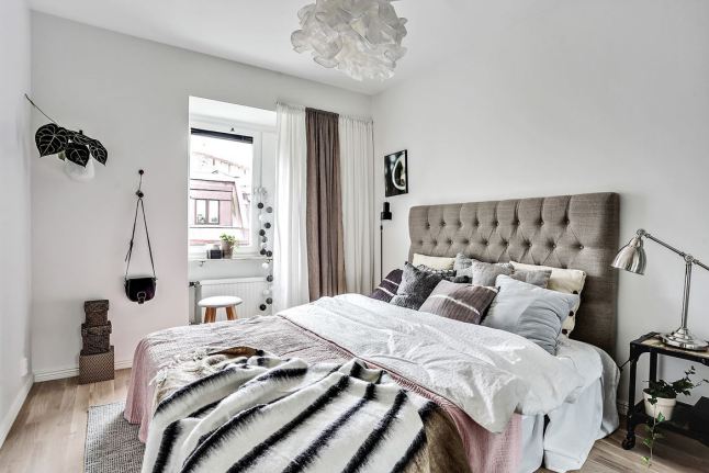 Pikowane szare wezgłowie łóżka w skandynawskiej aranżacji sypialni
