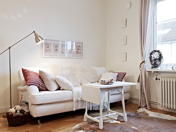 Biały składany stolik kawowy,srebrna lampa podłogowa i biała sofa w salonie
