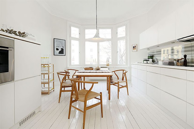 Skandynawskie wnętrze,biała kuchnia,drewniany stół,krzesła w naturalnym kolorze drewna,drewniane meble,biała podłoga