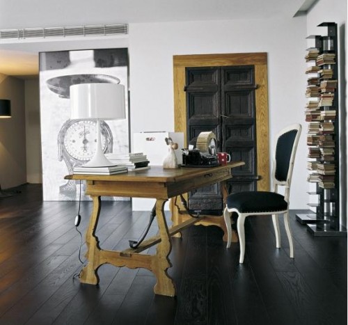 Drewniane czarne drzwi,czarne deskin apodłodze,rustykalne biurko i czarno-biała fototapeta w domowym biurze