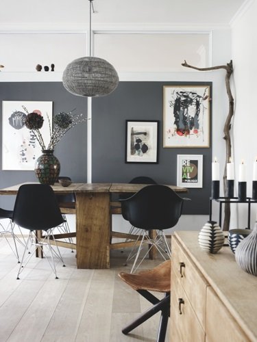 Drewniany stół vintage z nowoczesnymi czarnymi krzesłami i ażurową czarną lampą i ścianami