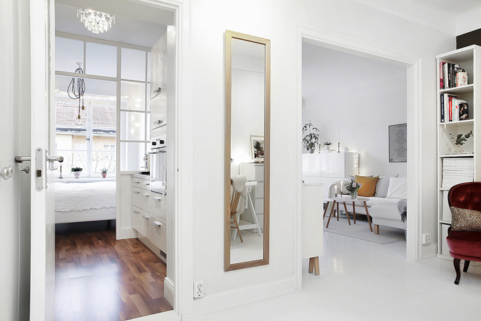 Białe i drewniane podłogi w mieszkaniu urządzonym w stylu skandynawskim