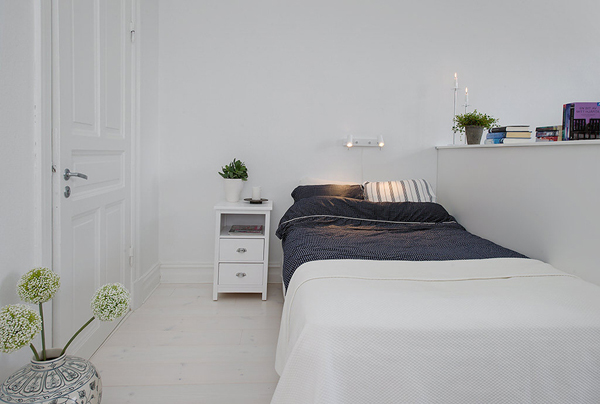 Biala sypialnia skandynawska z szarą ciemna narzuta na łóżko