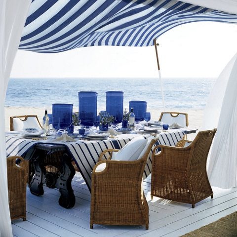 Nadmorski taras z rattanowymi fotela i w biało-niebieskiej aranżacji