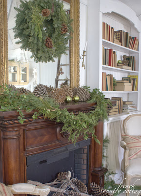 Świąteczna dekoracja kominka z zielonych gałązek i szyszek