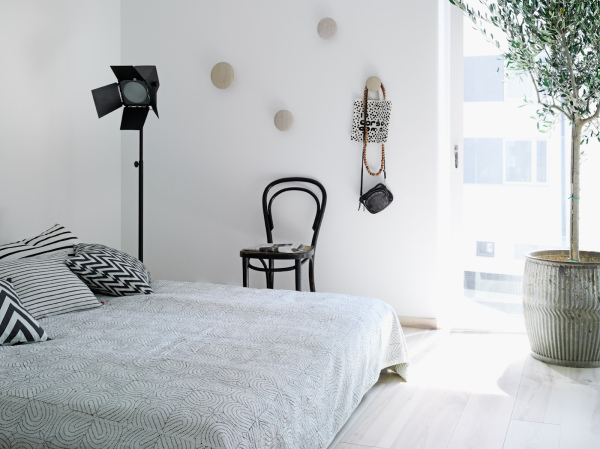Biało-czarne poduszki,czarne krzesło i lampa w sypialni