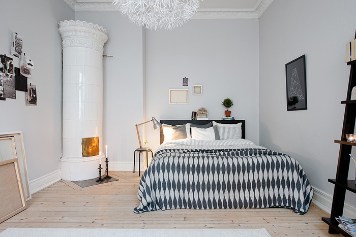 Biała sypialnia z okragłym piecem i czarnymi dekoracjami