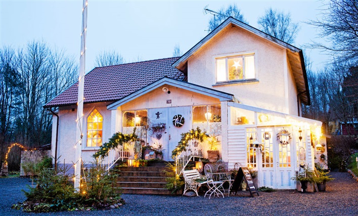 Świąteczne zielone girlandy,zielone wianki z lampkami i choinki w świątecznej aranżacji białego domku w stylu skandynawskim