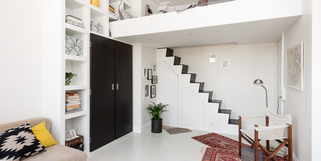 Biało-czarne schody  na antresole z łóżkiem  z wbudowanymi schowkami  w salonie  , czarna szafa wbudowana w ścianę z półkami