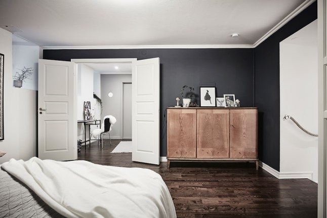 Czarne ściany i białe drzwi w  sypialni w tradycji skandynawskiej