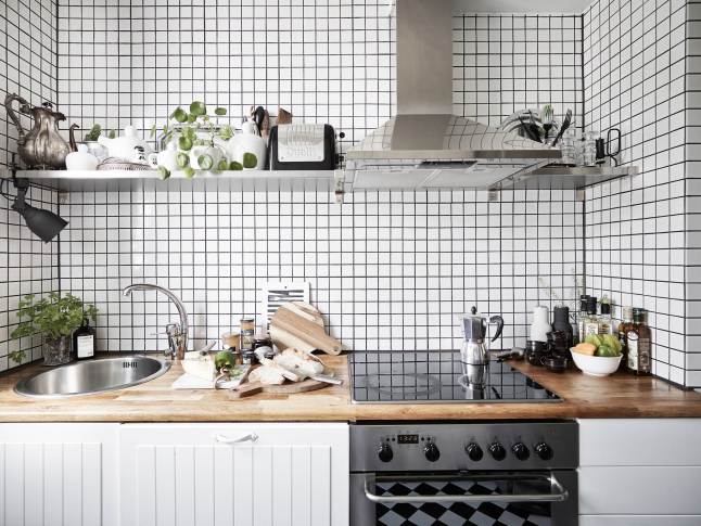Biala kuchnia skandynawska z drewnianym blatem,stalowym okapem z półkami i białą kosteczką płytką na ścianie