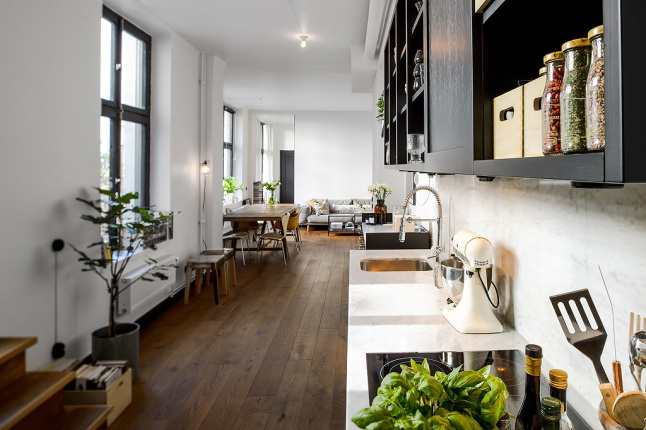 Czarno-biala kuchnia w otwartej przestrzeni mieszkania w zaadaptowanej fabryce