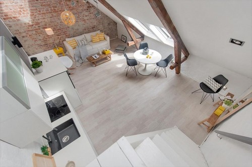 Poddasze w otwartym widoku salonu z kuchnią ze ścianą z cegły i podłogą z naturalnych desek