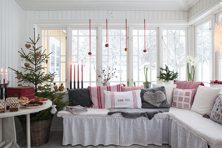 Biała weranda w zimowej świątecznej oprawie,biało-czerwone poduszki świąteczne,naturalna choinka z dekoracyjnymi serduszkami