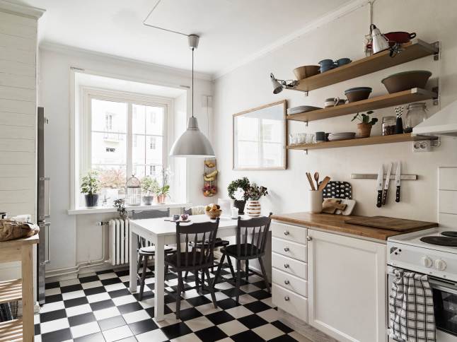 Biała kuchnia skandynawska z drewnianymi półkami,posadzka w czarno-białą szachownicę