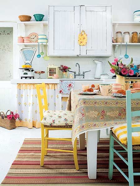 Wiejska kuchnia z żółtymi i turkusowymi krzesłami,tkanymi kolorowymi dywanikami w paski,kwiecistym obrusem i dodatkami z emaliowanej blachy