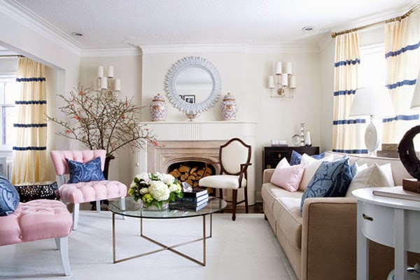 Różowe pikowane fotele,białe zasłony w niebieskie pasy,okrągłe lustro nad kominkiem i szklany metalowy stolik w eklektycznym salonie