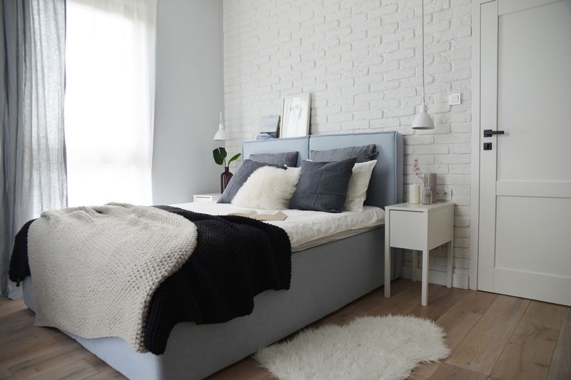Białe cegły w sypialni z błękitnymi dodatkami