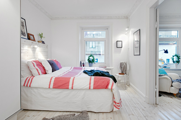 Białe łóżko z drewna z pościelą w różowe paski