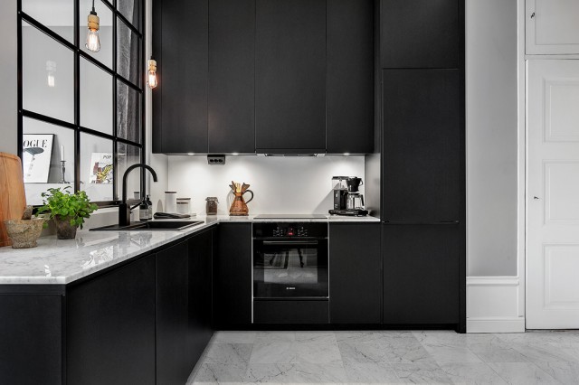 Czarna nowoczesna kuchnia z marmurowymi blatami i podłogą oraz przeszkloną ścianką z czarnymi metalowymi ramami