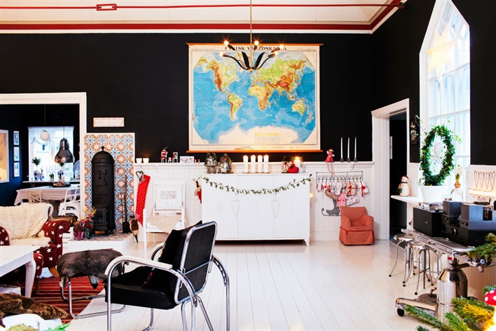 Czarna ściana,biała podłoga z desek,białe drewniane meble i kolorowe dekoracje świąteczne w skandynawskim stylu