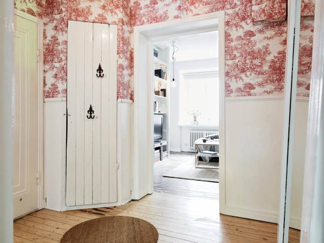 Rustykalny przedpokój z białymi wiejskimi drzwiami szafy i stylową tapetą na ścianie