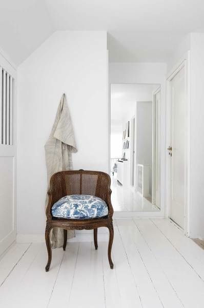Francuski brązowy fotel z rafii ,biała zabudowa szaf,białe malowane deski w przedpokoju