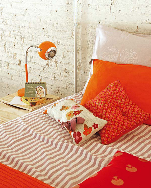 Biała cegła na ścianie i  żywioł pomarańczowych detali w sypialni