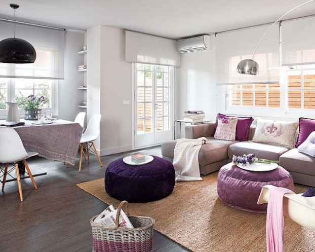 Szaro-beżowa podłoga w białym salonie z wrzosowymi i fioletowymi pufami i poduszkami