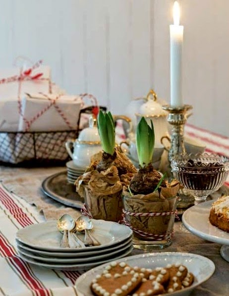 Klasyczny metalowy świecznik,świateczna biało-złota porcelana,cynowa taca,szklane pucharki i świąteczne paczuszki na stole