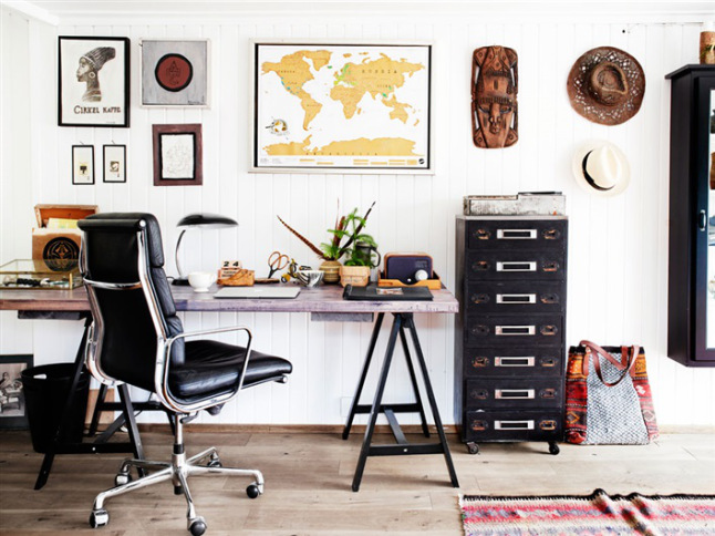 Biurko skandynawskie na kozłach,metalowa wąska i wysoka komoda w czerni i domowa galeria zdjęć i grafik na ścianie w domowym biurze