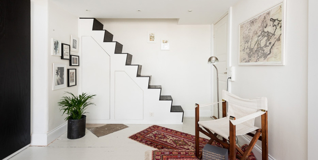 Biało-czarne schody  na antresole z łóżkiem  z wbudowanymi schowkami  w salonie