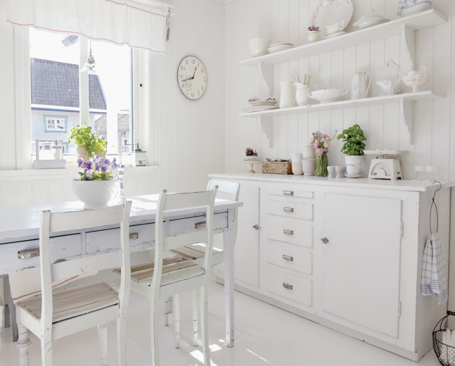 Skandynawska biała kuchnia z komodą, półkami i bialym stołem z szufladami